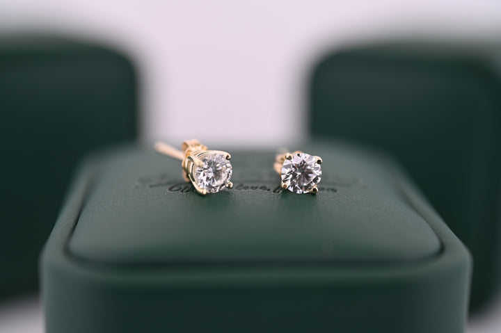 Cercei din aur cu diamante naturale "Selene" pentru femei, eleganți și rafinați, ideale ca cadou de lux, pe fundal verde.