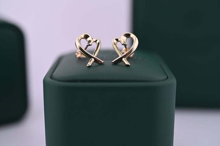Cercei Aur Eros din aur galben, simbolizând iubirea și eleganța, ideali ca un cadou premium pentru femei, pe un fundal verde elegant.
