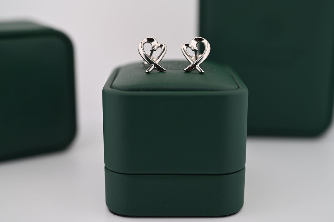 Cercei Eros de platină pe suport elegant verde, simbolizând luxul și eleganța, ideali pentru un cadou rafinat.