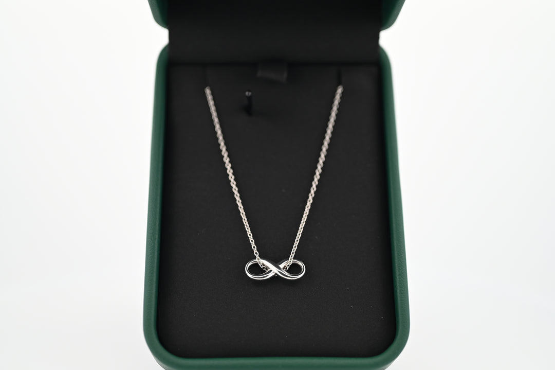 Elegant platinum infinity pendant necklace in a black velvet box, symbolizing timeless elegance and durability.