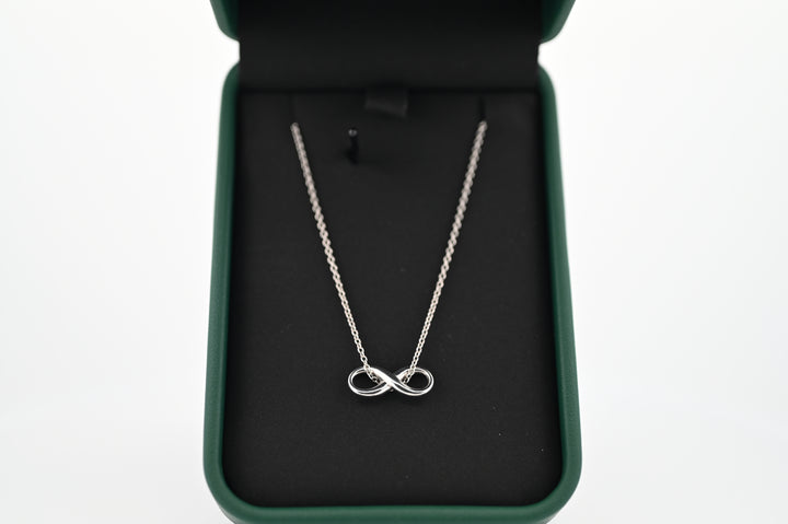 Elegant platinum infinity pendant necklace in a black velvet box, symbolizing timeless elegance and durability.