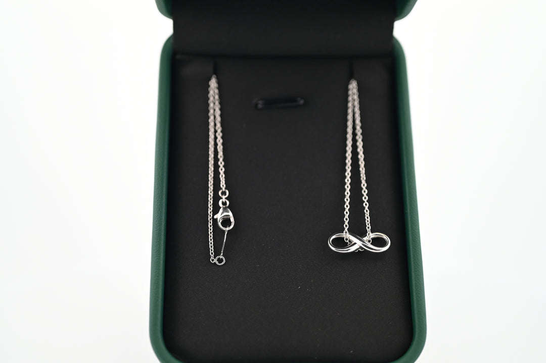 Platinum necklace with infinity pendant in a jewelry box, symbolizing elegance and timeless luxury.