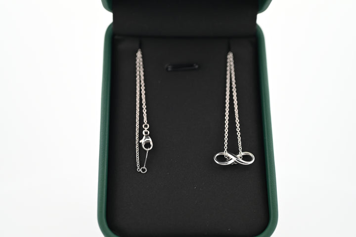 Platinum necklace with infinity pendant in a jewelry box, symbolizing elegance and timeless luxury.