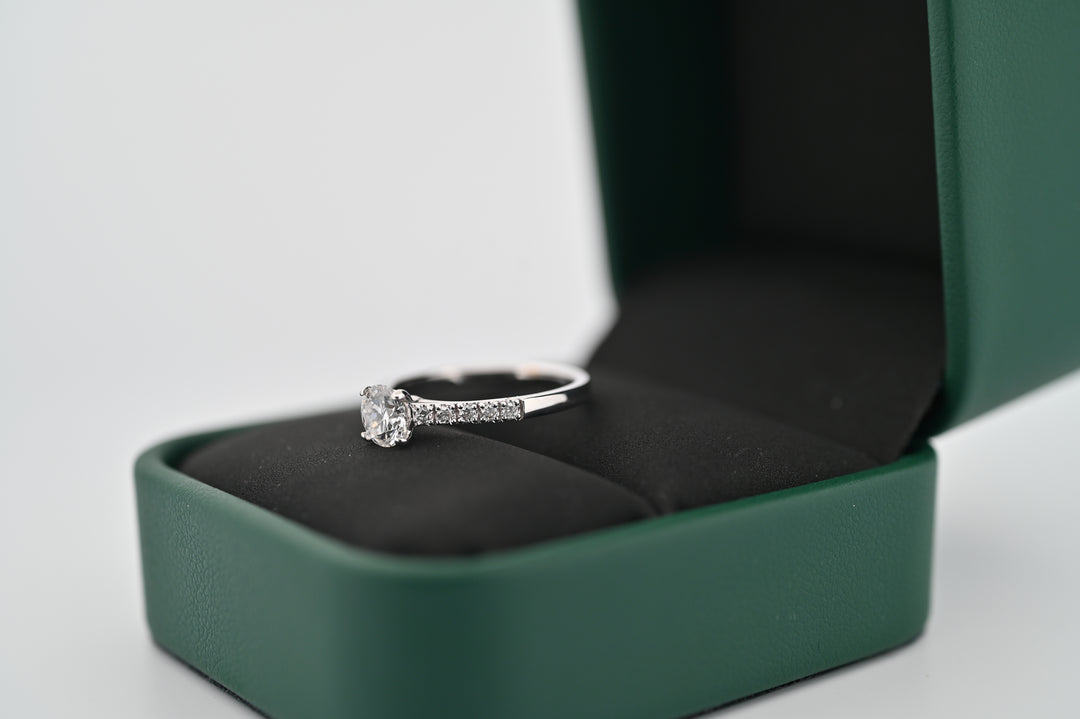 Inel de logodnă elegant din platină, cu diamant central de 0.5 Carat și 10 diamante mici, prezentat într-o cutie de lux, cadou perfect pentru ea.