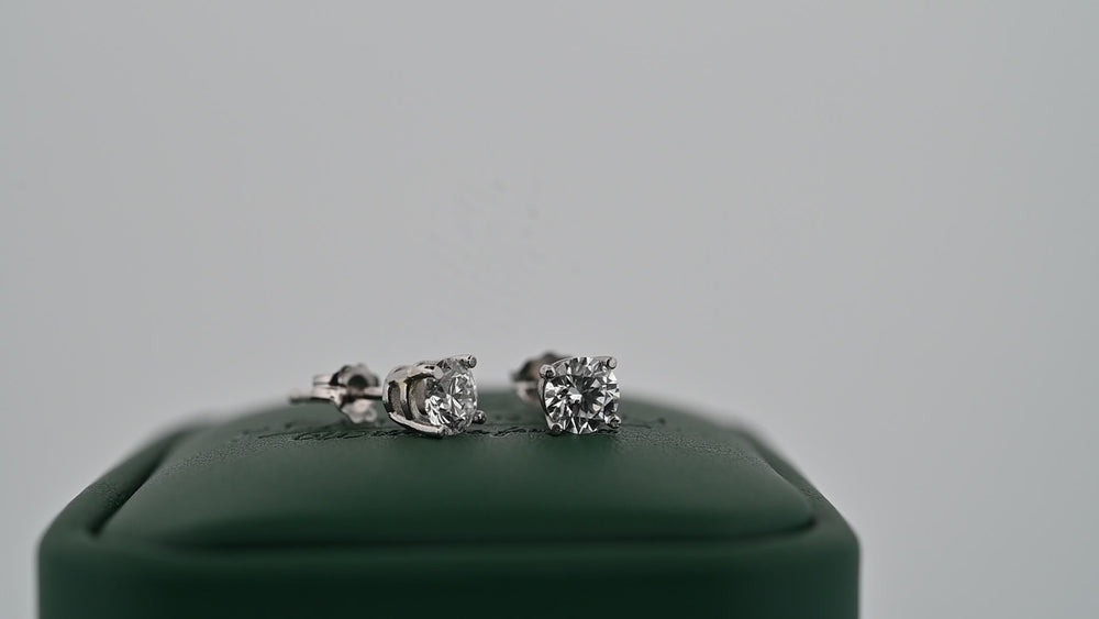 Cercei din platină 0.6ct cu diamante naturale strălucitoare pe suport verde, simbolul eleganței și rafinamentului.