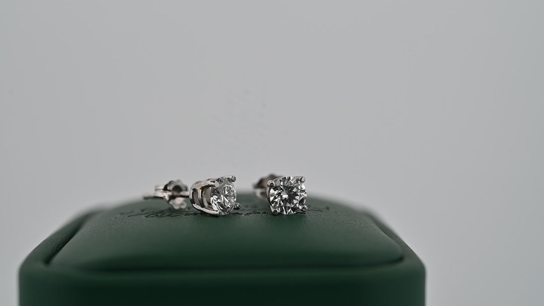 Cercei din platină 0.6ct cu diamante naturale strălucitoare pe suport verde, simbolul eleganței și rafinamentului.