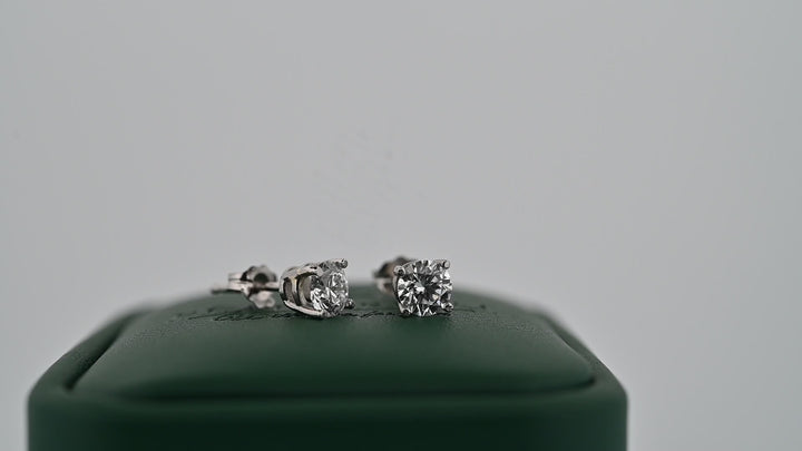 Cercei din platină 0.6ct cu diamante naturale strălucitoare pe suport verde, simbolul eleganței și rafinamentului.